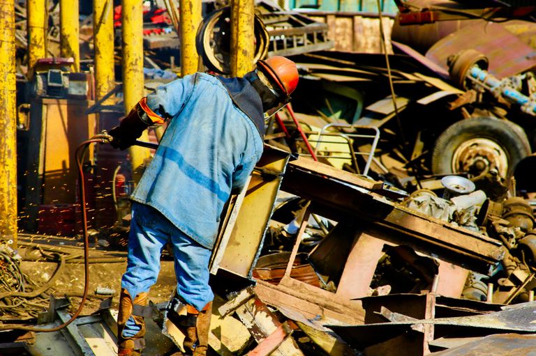 Ein Arbeiter auf einem Schrottplatz der voll mit Müll ist